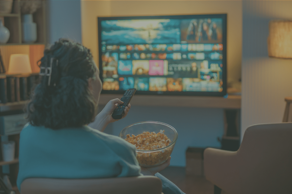 Woman holding popcorn and remote while watching TV